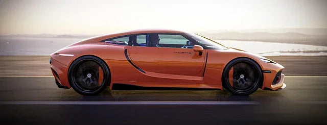 Orange luxury sports car driving on coastal highway under clear sky, showcasing sleek design and black alloy wheels