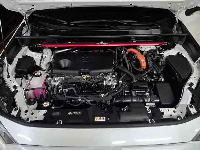 Clean engine bay of a white Toyota car featuring OEM components and a red aftermarket strut bar
