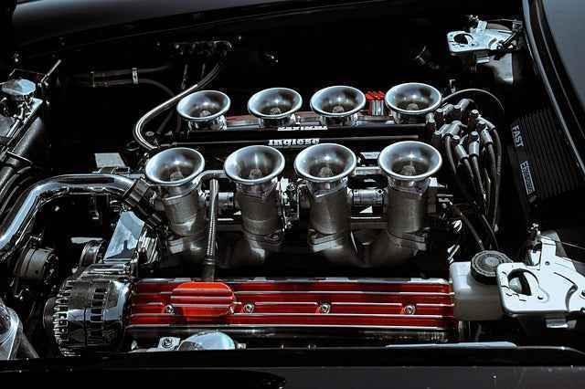 High-performance car engine with polished carburetors and red valve cover under hood