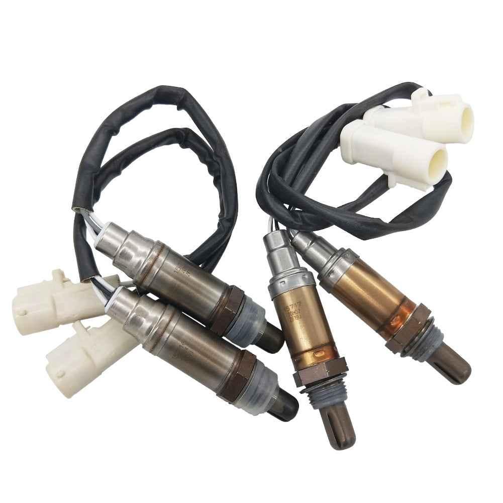 Set of four automotive oxygen sensors with wiring and white connectors on white background