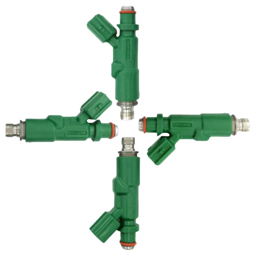 Set of four green OEM fuel injectors for automotive engines arranged on white background