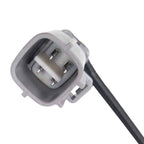 Close-up of a gray automotive electrical connector with four metal pins and attached black wire