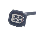 Close-up of a black automotive electrical connector plug with four metal terminals on white background